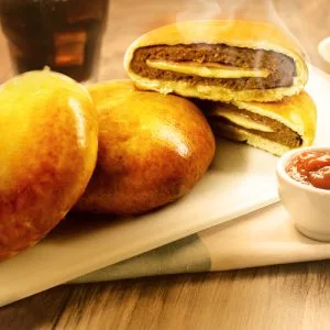 Imagem de X-Duplo assado cortado ao meio, com vapor saindo, mostrando recheio cremoso.